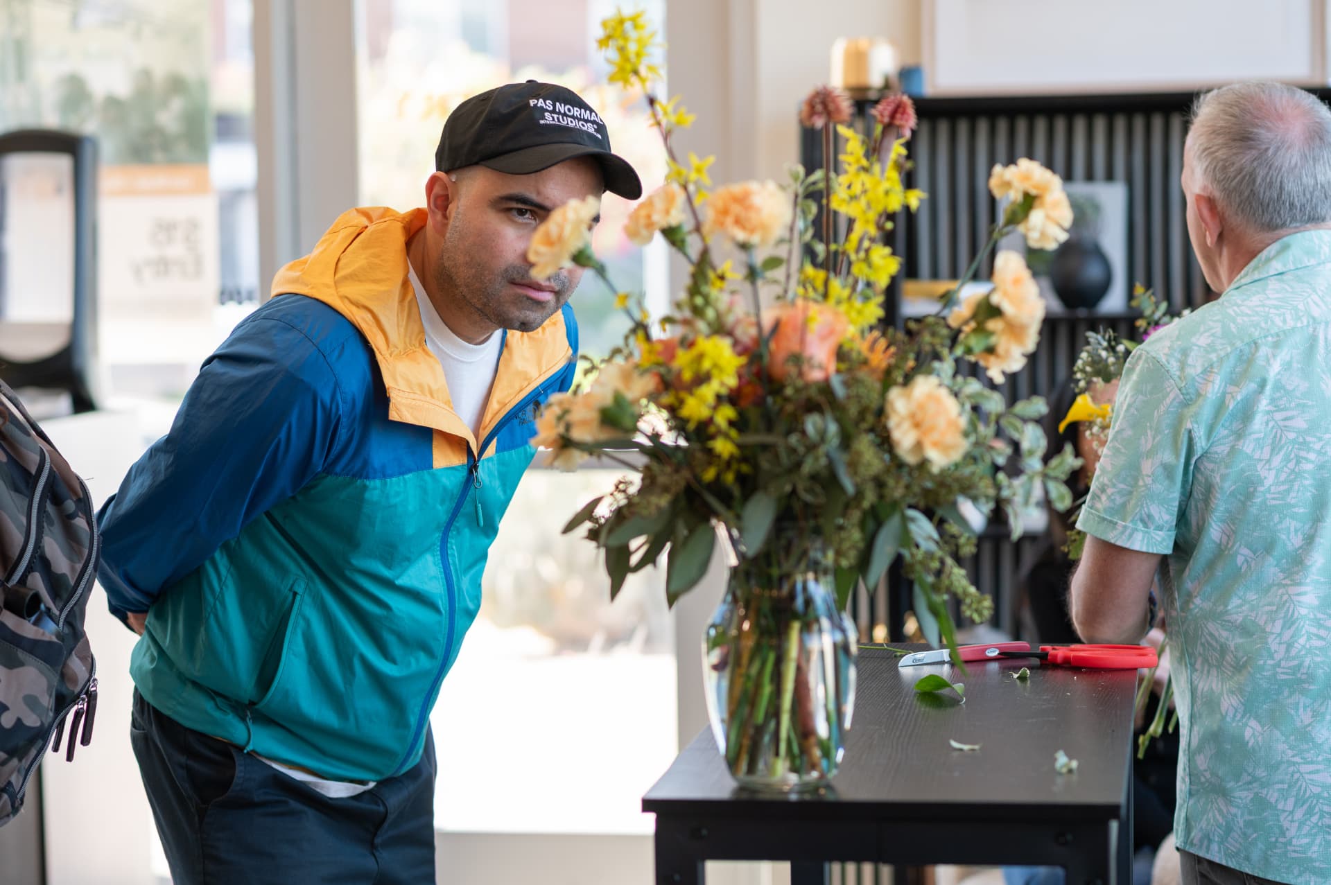 A guest browsing fresh stems at the Stemistry flower bar beside the coffee counter