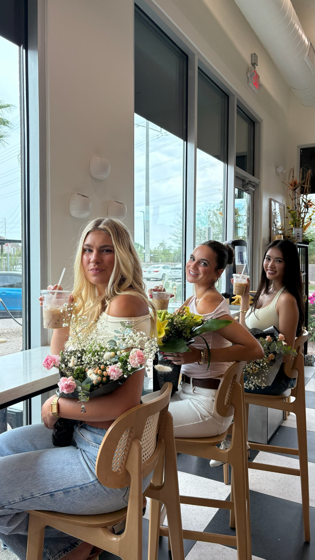 Three friends at the window bar with iced coffees and hand-tied bouquets at Stemistry South Scottsdale