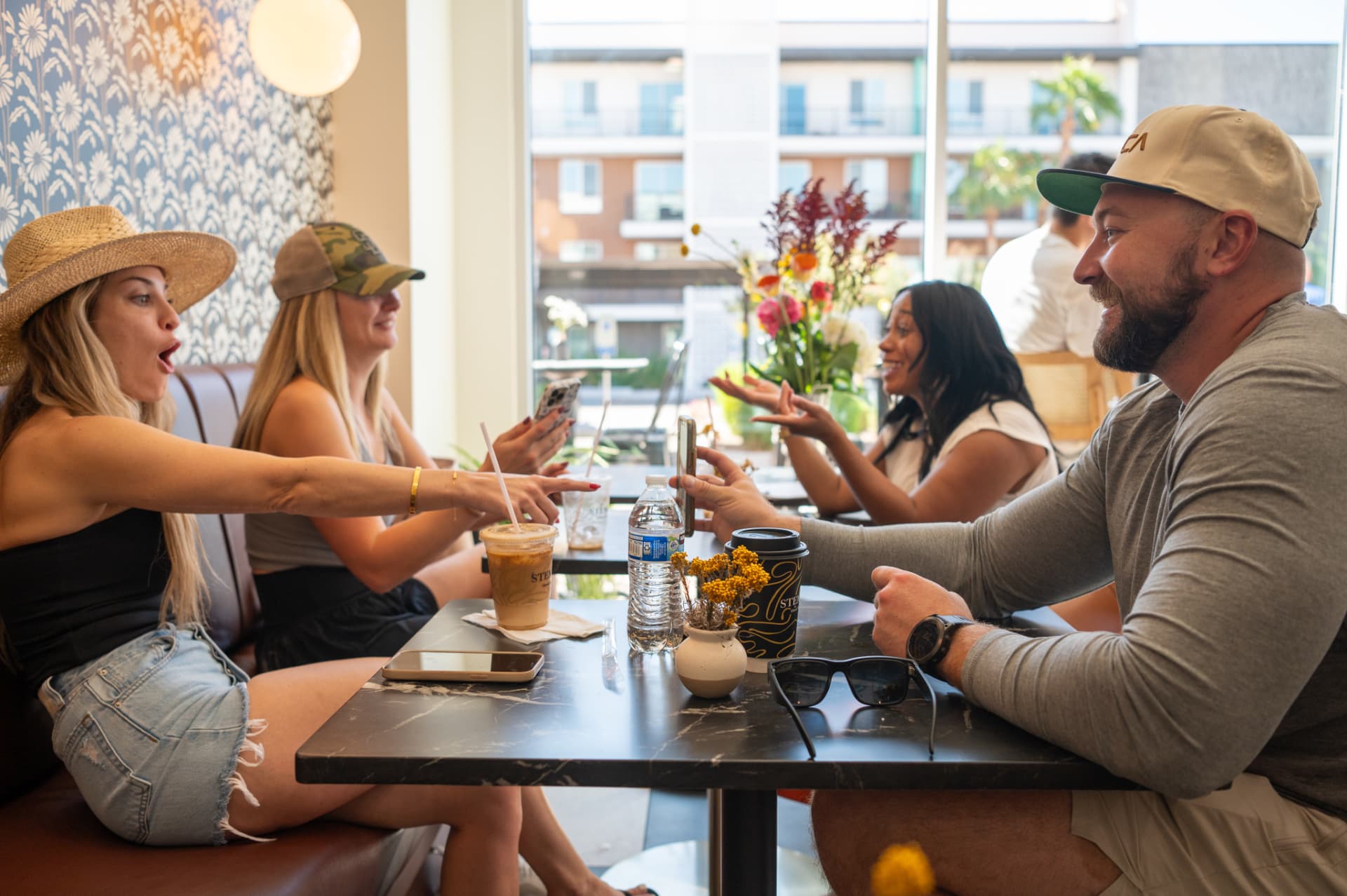 Friends catching up over iced coffee by the front windows